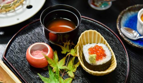 a black plate of food with a cup of tea at Ryokan Hirayama in Ueki
