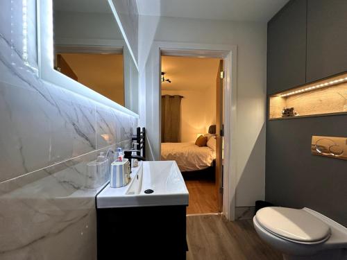 a bathroom with a sink and a toilet and a bed at Centrally Located Modern 2 Bedroom Apartment, Minutes Walk to AO Arena in Manchester