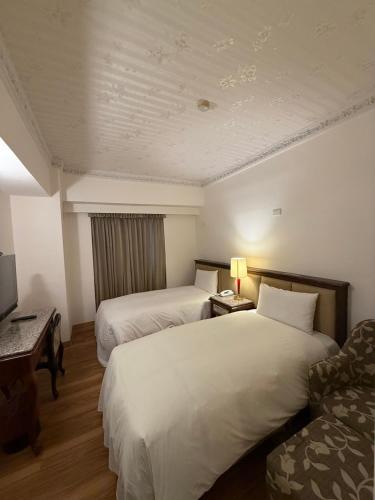 a hotel room with two beds and a couch at Hua Tong Hotel in Hualien City