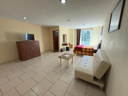 a living room with a couch and a bed at Hotel Ciprés Puebla in La Concepción