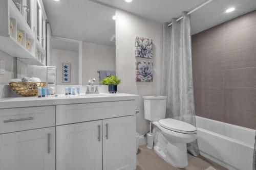 a white bathroom with a toilet and a sink and a tub at Luxury - 2BR 2BA - Balcony - Right Across From the Beach in Boca Raton