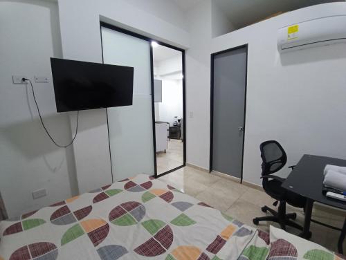 a bedroom with a bed and a desk and a television at San Luis Apartamento 302 Cúcuta in Cúcuta