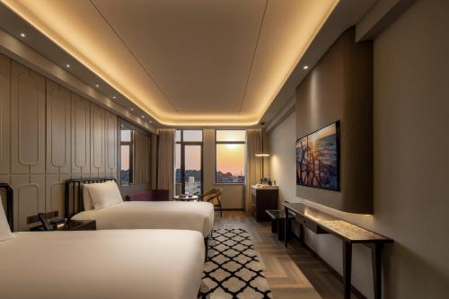 a hotel room with two beds and a table at Xiamen Lujiang Harbourview Hotel in Xiamen