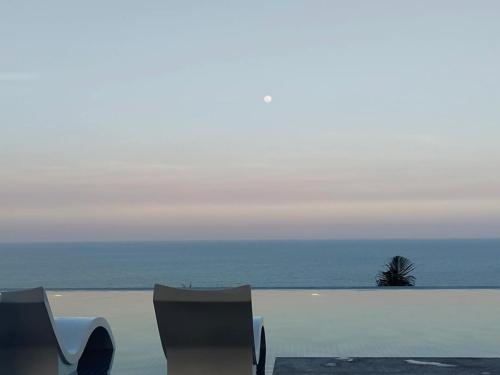 a view of the ocean with a white wall and a palm tree at Khách Sạn Apec Mũi Né Phan Thiết in Ấp Thiẹn Ái