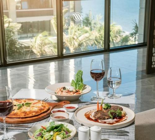 a table with plates of food and glasses of wine at Khách Sạn Apec Mũi Né Phan Thiết in Ấp Thiẹn Ái