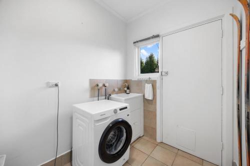a white laundry room with a washing machine and a window at Mediterranean Muse - 3BR, Wi-Fi, Parking in Unley