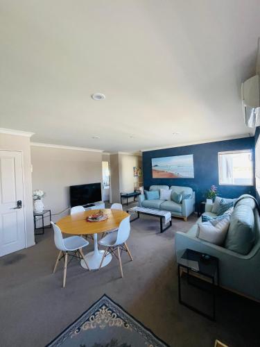a living room with a table and a couch at Beach Apartment in Papamoa