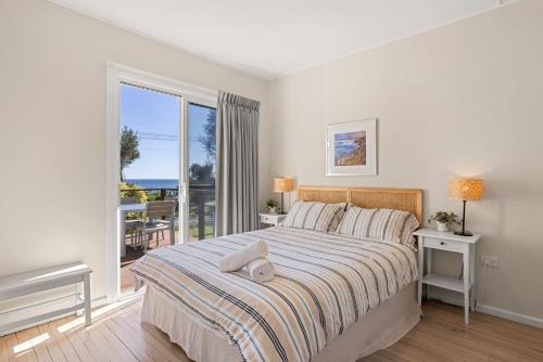 a bedroom with a large bed and a balcony at Beachhouse Currarong - Pet Friendly Beachfront in Currarong