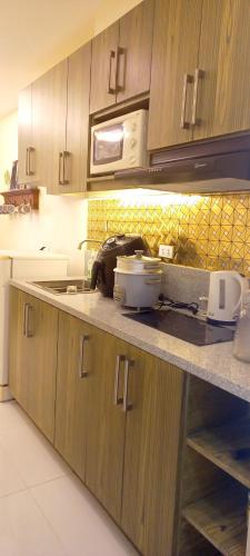 a kitchen with wooden cabinets and a counter top at Cozy & comfy staycation in Quezon City in Manila
