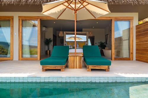 two chairs and an umbrella next to a swimming pool at Wild Cottages Elephant Sanctuary Resort in Amphoe Koh Samui