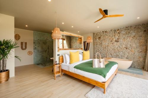 a bedroom with a large bed and a bath tub at Wild Cottages Elephant Sanctuary Resort in Amphoe Koh Samui