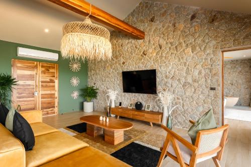 a living room with a couch and a tv at Wild Cottages Elephant Sanctuary Resort in Amphoe Koh Samui