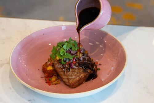 a pink bowl of food with sauce being poured onto it at Grand Westside Manila Bay in Manila