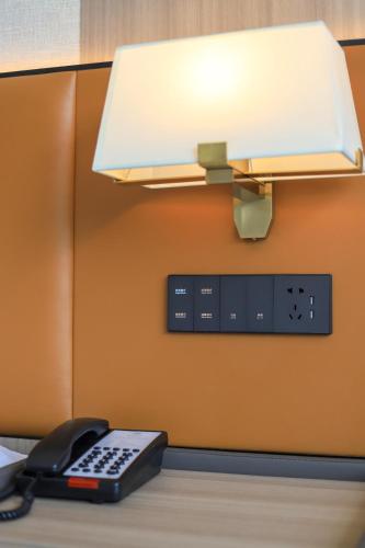 a desk with a phone and a lamp on it at Dujiangyan Yuandong Yaju Hotel in Dujiangyan