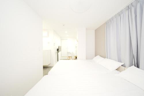 two beds in a white room with white curtains at GLOU Koiwa Tokyo - Economic APT in a Japanese Local Shopping Street, with Direct Access to Shinjuku & Akihabara in Tokyo