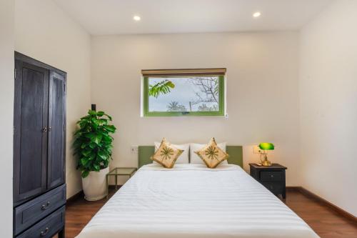 a bedroom with a large white bed and a window at Indochine apartment in An Bàn (2)