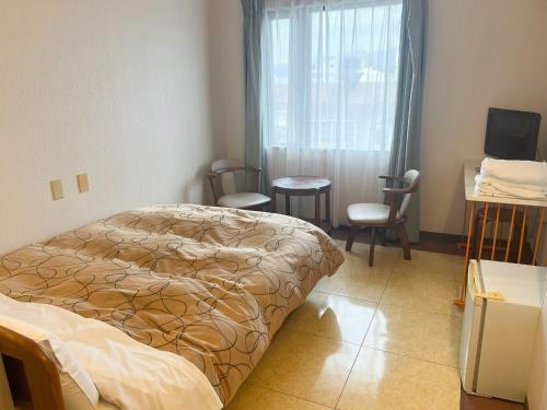 a bedroom with a bed and chairs and a window at Hotel Yamadaso - Vacation STAY 10209v in Nago