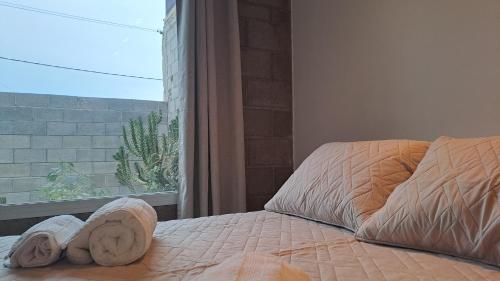 a bed with a pair of towels on it next to a window at Prunus departamentos in Comodoro Rivadavia