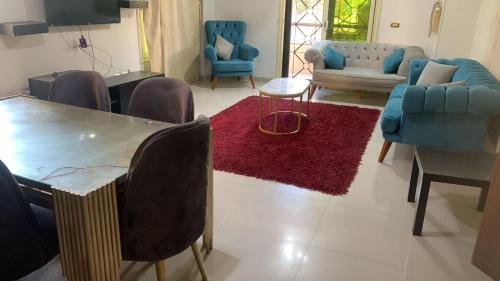 a living room with blue chairs and a table and a red rug at 2 Bedrooms Apartment beside American University in New Cairo in Cairo