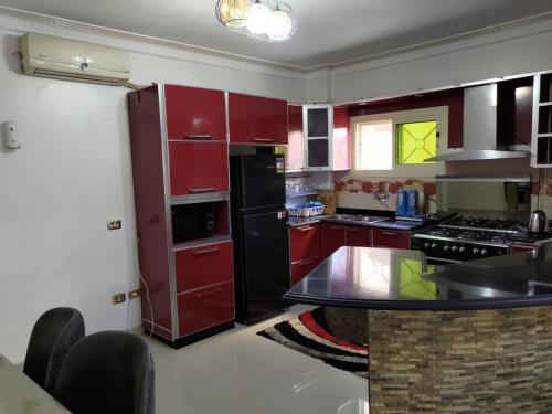 a kitchen with red cabinets and a black refrigerator at 2 Bedrooms Apartment beside American University in New Cairo in Cairo