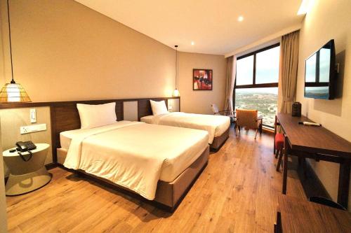 a hotel room with two beds and a desk at Khách Sạn Apec Mũi Né Phan Thiết in Ấp Thiẹn Ái