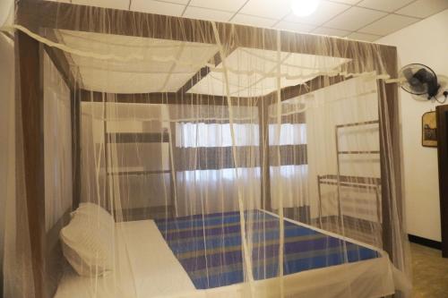 1 dormitorio con cama con dosel y suelo azul en Villa Mahawella, en Galle