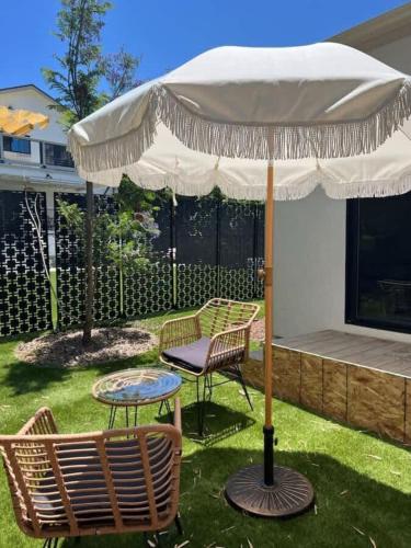 an umbrella and two chairs and a table in a yard at The Quaint Cardiff Hideaway with Pak N Play in Encinitas