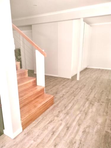 an empty living room with wood floors and stairs at Private Bush & Beach Retreat in Eudlo
