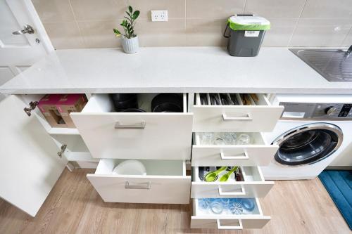 a kitchen with white drawers and a washing machine at Stylish House 8mins walk to Figtree Grove in Figtree
