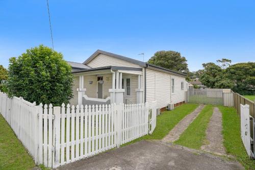 a white picket fence in front of a house at Stylish House 8mins walk to Figtree Grove in Figtree