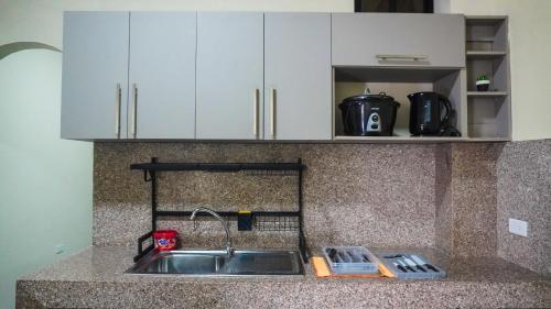 a kitchen counter with a sink and white cabinets at Departamento completo, facso in Cuatro Hermanas