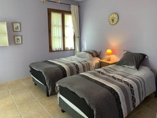 - une chambre avec 2 lits et une horloge murale dans l'établissement Propriété aux Eyzies avec piscine privée pour 6 personnes - FR-1-824-12, à Manaurie