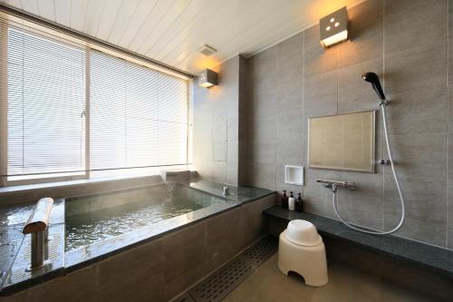 a bathroom with a tub with a shower and a toilet at Hakone Hisui in Hakone