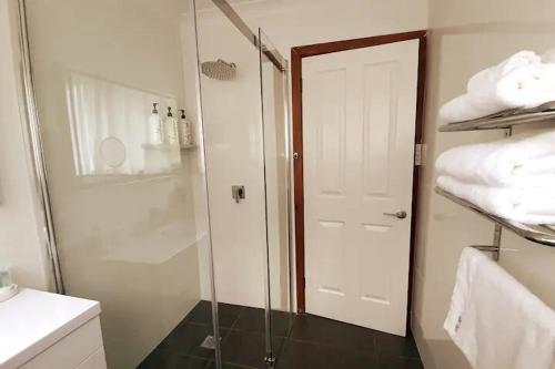 a bathroom with a shower and a glass door at 3BR Home 2 min drive to UOW, with garage, AC, Wi-Fi in Keiraville