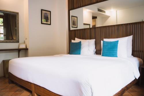a bedroom with a large white bed with blue pillows at Le Sen Boutique Hotel in Luang Prabang