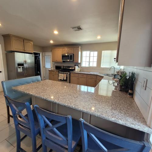 a kitchen with two blue chairs at a counter at 3 bedroom 2 bath home with Jacuzzi near Beverly Hills, wi-fi, Jacuzzi, Roku, BBQ, giant games family fun in Los Angeles