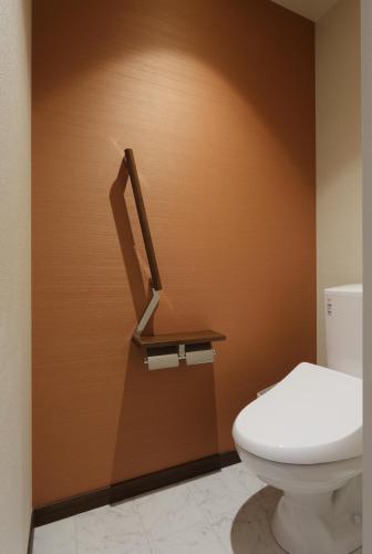a bathroom with a toilet and a brown wall at HOTEL PROMOTE HIROSHIMA in Hiroshima