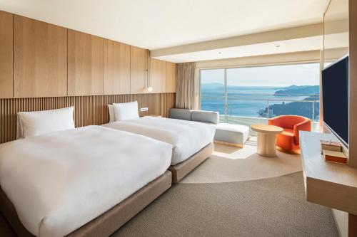 a hotel room with two beds and a large window at Hotel Grand Bach Atami Crescendo in Atami