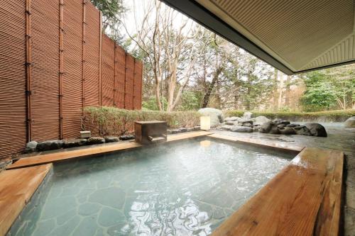 a swimming pool in a garden with a wooden floor at Hakone Hisui in Hakone