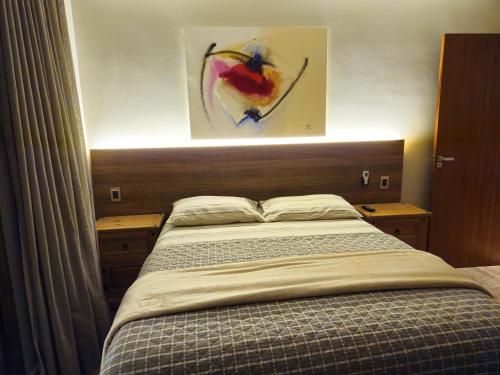 a bedroom with a bed and a painting on the wall at 6 suítes com sofisticação e conforto na Praia do Forte! in Praia do Forte