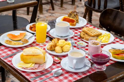 a table topped with plates of breakfast foods and drinks at VELINN Pousada Casa de Campos Mountain House in Campos do Jordão