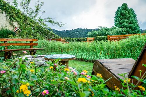 a picnic table and benches in a garden with flowers at VELINN Pousada Casa de Campos Mountain House in Campos do Jordão