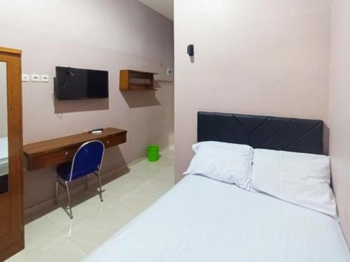 a bedroom with a bed and a desk and a tv at De Corner 2 Madiun RedPartner in Madiun