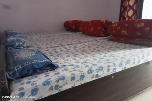 a bed with blue and red pillows on it at Hotel Shri Kedar Mangalam By StayApart in Phata