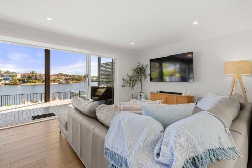 a living room with a large couch and a large window at Watersedge - Absolute Waterfront in Sussex inlet