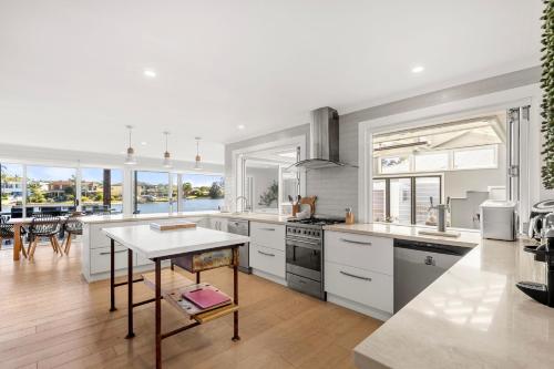 a kitchen with white cabinets and a table in it at Watersedge - Absolute Waterfront in Sussex inlet