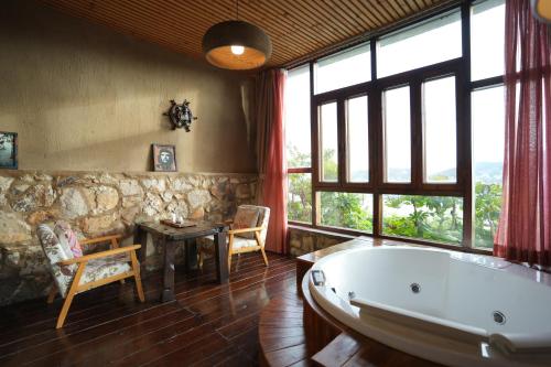a large bathroom with a tub and a table and chairs at 温岭海山生活石屋民宿 in Shangma