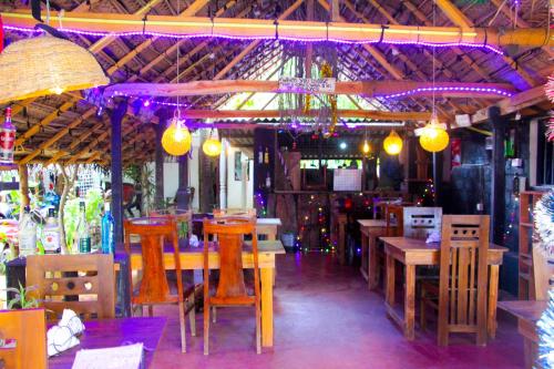 a restaurant with wooden tables and chairs and purple lights at Mom's Homestay in Sigiriya