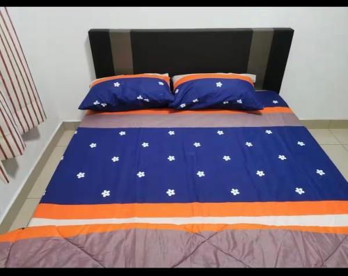 a bed with an orange and blue comforter and pillows at Connaught Avenue in Kuala Lumpur
