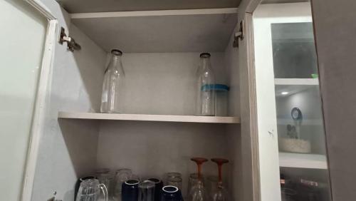 a cabinet filled with glass bottles in a room at Homestay at Rishikesh - 1BHK Apartment in Rishīkesh